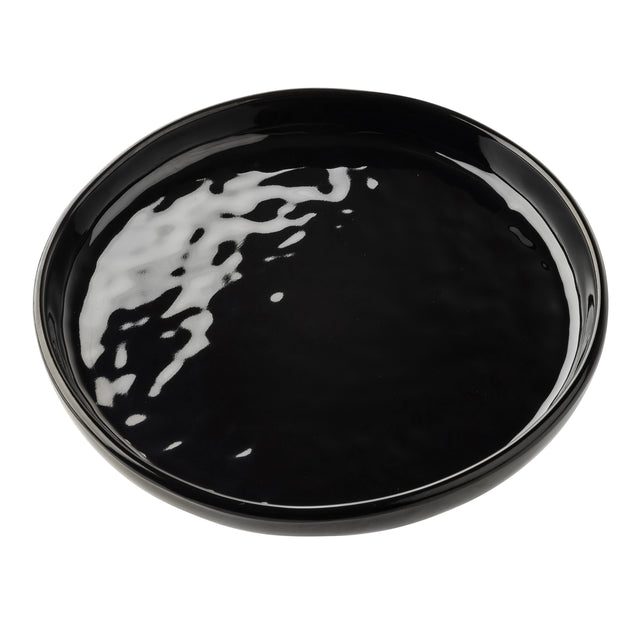A round, glossy black ceramic serving plate with slightly raised edges sits on a white background. Light reflections highlight its smooth, shiny surface, emphasizing its minimalist and modern design. The plate is empty.