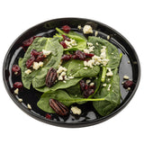 A black Ridge Collection Serving Plate with fresh spinach leaves, topped with candied pecans, dried cranberries, and crumbled blue cheese. The salad ingredients are spread evenly across the durable melamine plate on a white background.