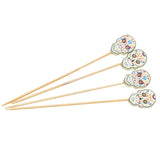 Four wooden bamboo picks with decorative sugar skulls at the top, each featuring colorful floral and swirl patterns inspired by Day of the Dead. Arranged in a fan shape, these festive decorative picks stand out against a plain white background.