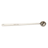 A stainless steel coffee scoop with a long handle and a round bowl. The handle is stamped with “5 ml / 1 tsp,” and has a small hole at the end for hanging. The spoon is shown against a plain white background.