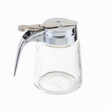 A modern glass dispenser, this 8 oz. syrup jar features a wide body, shiny silver metal lid, and a hinged lever handle for easy pouring. Dishwasher safe and empty, it’s displayed on a white background.