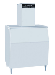 A large, rectangular commercial nugget-style ice maker with angled front door, four metal legs, and a tall box housing labeled "Commercial Ice Machine" on top. The light gray machine stands against a plain, light background.