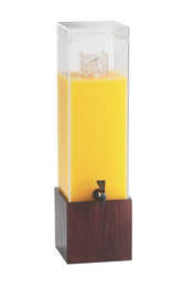 A tall, clear Westport Beverage Dispenser with a 3 gallon BPA Free capacity is filled with orange juice and ice cubes. It features a black spigot near the base, set in a dark wooden square stand against a plain white background.
