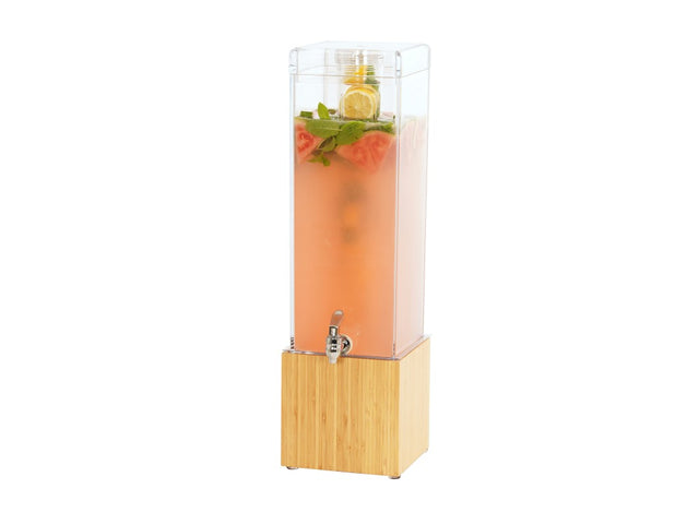 A tall, clear BPA free beverage dispenser with a silver spout and a bamboo base holds pink liquid with watermelon slices, lemon slices, and mint leaves floating at the top. The dispenser is set against a plain white background.