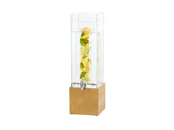 A tall, clear Madera Beverage Dispenser with a silver spigot sits on a wooden base. This 3 gallon infuser holds water with lemon and lime slices stacked vertically inside. The background is plain white.