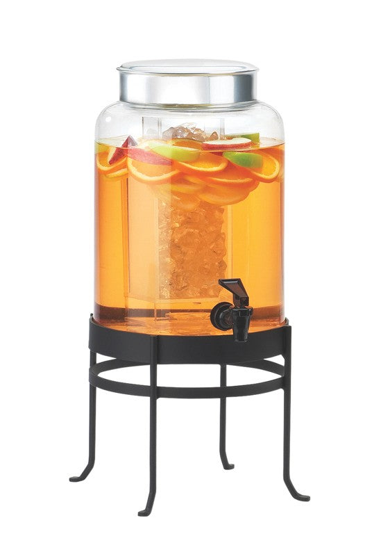 A 2-gallon glass beverage dispenser filled with orange liquid, ice, and citrus slices sits on a black metal stand. It features a silver lid and a black spigot near the bottom for easy pouring.