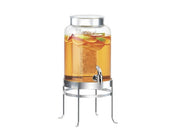 The SoHo Beverage Dispenser is a 2 gallon glass beverage dispenser filled with iced tea, lemon and orange slices. It features a silver lid, convenient spigot, and sits on a tall silver metal stand against a plain white background.