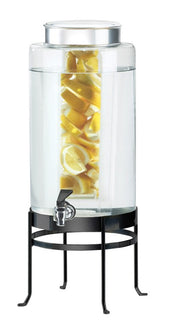 A large BPA Free beverage dispenser filled with water and lemon slices in an infusion chamber, featuring a silver lid, a spigot at the bottom, and sitting on a tall black metal stand.