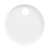 A round, flat white plate is shown from above. The plate, which is dishwasher safe, has a single large circular hole near the rim and a small raised bump in the center. The plain white background highlights its smooth surface and unique features.