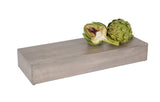 A whole artichoke and a halved artichoke with a purple center rest on a rectangular Cal-Mil Aspen Riser made of gray-washed pine wood, set against a white background.