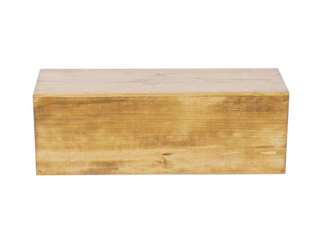 A plain rectangular wooden display riser with a smooth, light brown finish sits on a white background. The grain and subtle markings of the rustic pine are visible, and the box appears closed, with no visible handles or decorations.