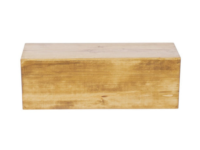 A plain rectangular wooden display riser with a smooth, light brown finish sits on a white background. The grain and subtle markings of the rustic pine are visible, and the box appears closed, with no visible handles or decorations.