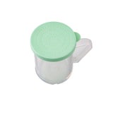 A transparent BPA-free plastic dredge shaker with a handle and a light green perforated lid, ideal for sprinkling fine ground spices. The evenly spaced holes in the lid ensure precise seasoning, all photographed against a plain white background.