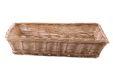 A rectangular handwoven basket with an open top, crafted from light brown reeds. The basket features slightly slanted sides and a flat base, with visible gaps between the woven strands. It is empty and sits on a white background.