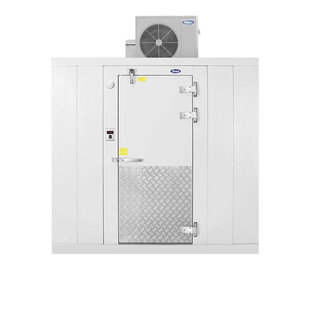 A large, white commercial walk-in freezer features a central metal door, silver diamond plate panel below, heavy-duty hinges, control panel on the left, and a refrigeration unit mounted on top against a plain white background.