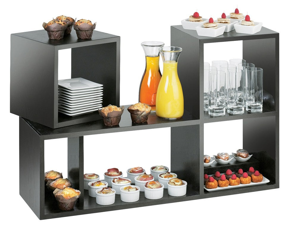 A black Cal-Mil Midnight Bamboo Library Display shelf holds muffins, desserts, orange and yellow juice in carafes, stacked plates, clear glasses, and assorted mini pastries—neatly arranged for a buffet or catered event.