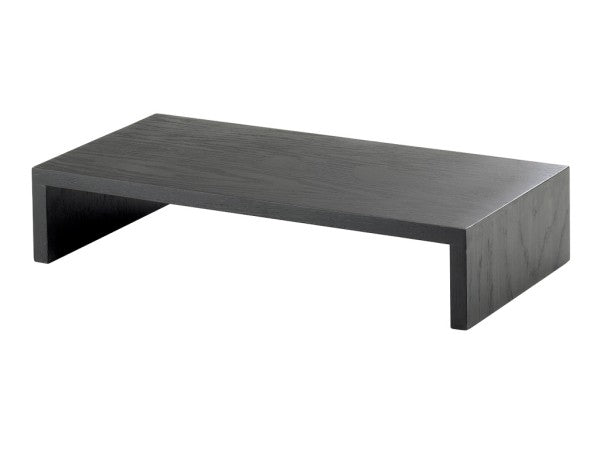 A minimalist black wooden monitor stand, inspired by the Cal-Mil Midnight Bamboo Step Riser, features a rectangular top with open sides for a modern arch look. Subtle wood grain texture adds elegance against the plain white background.
