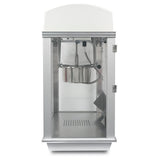 A silver and white Whiz Bang Popcorn Machine with a glass front showcases a stainless steel kettle hanging at the top center. The door is slightly ajar on the right, and the bottom tray has small holes to catch unpopped kernels.