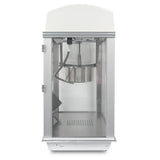 A sleek and modern Whiz Bang Popcorn Machine in silver and white sits on a flat surface. Its clear glass front reveals an empty interior, while the stainless steel kettle hangs at the top inside this stylish countertop popcorn machine.
