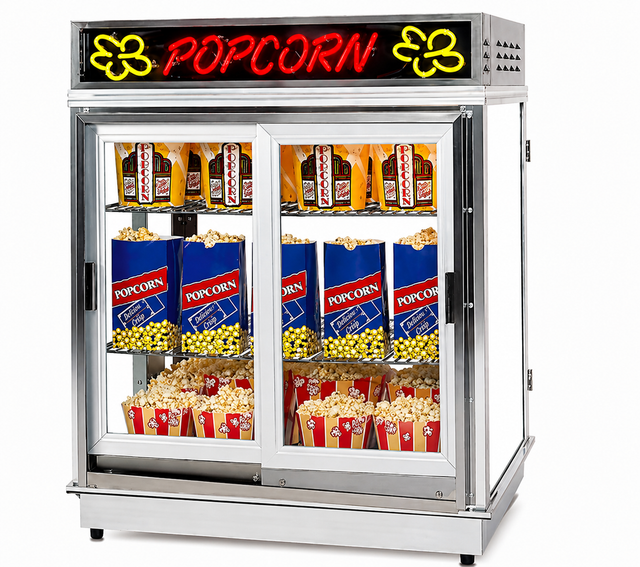 A large silver popcorn shelf warmer with a glass front displays bags and boxes of popcorn. The top has a red neon POPCORN sign with yellow popcorn illustrations, while the corn freshener system keeps the ready-to-serve popcorn fresh on the shelves.