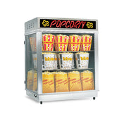 A glass popcorn display case with a black and red POPCORN sign on top, featuring a shelf warmer to keep several large, yellow-and-red-striped popcorn tubs and bags fresh on two shelves inside the case.