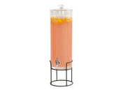 A tall, clear 3 gallon beverage dispenser with a spigot, filled with pink liquid and floating lemon slices, sits on a black metal stand. The dispenser has a glass lid and is isolated on a white background.