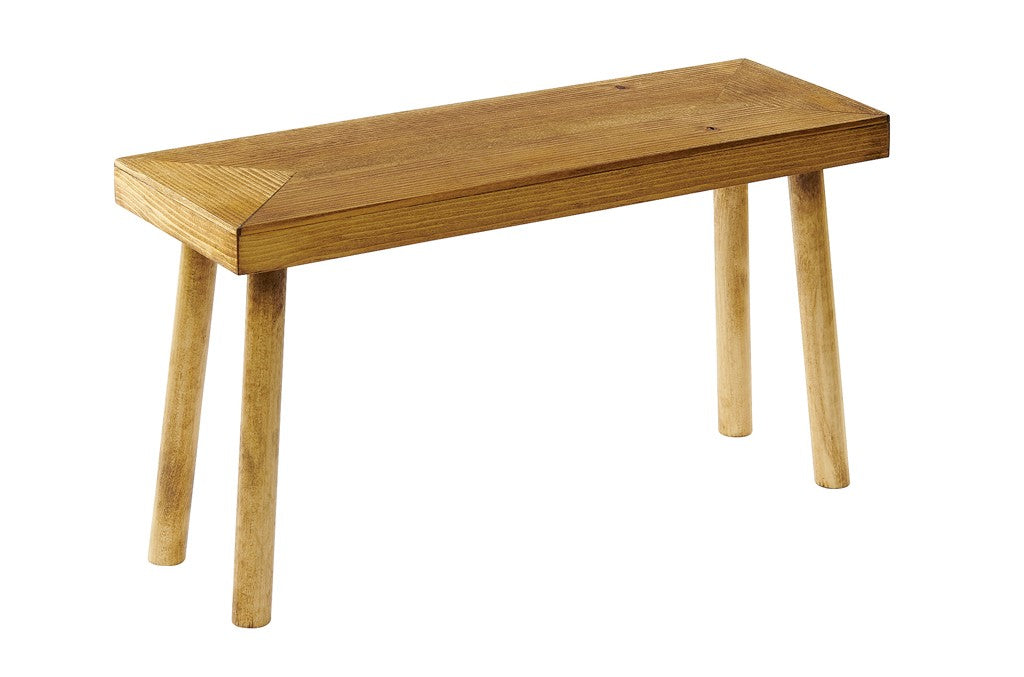 A small wooden bench with a rectangular seat and four round, angled legs. Crafted from rustic pine, the wood has a natural finish, showing the grain. The simple Cal-Mil design has clean lines and no backrest or armrests. Photo is on a white background.