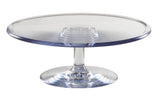 A clear polycarbonate cake stand with a round, flat top and a short, sturdy pedestal riser base. The smooth, reflective surface is empty and displayed against a plain white background.