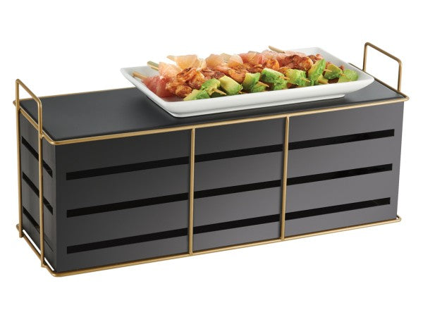 A rectangular, black and gold wire frame Cal-Mil Empire Riser holds a white plate filled with skewered food—meat, green vegetables, and other colorful ingredients. The stand features thin gold handles on both ends for easy carrying.