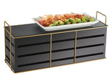 A rectangular, black and gold wire frame Cal-Mil Empire Riser holds a white plate filled with skewered food—meat, green vegetables, and other colorful ingredients. The stand features thin gold handles on both ends for easy carrying.