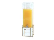 A tall, clear 3 gallon beverage dispenser filled with orange juice stands on a gold metal frame. The BPA free dispenser features a silver spigot near the bottom, a transparent lid on top, and a large ice block visible above the juice inside.