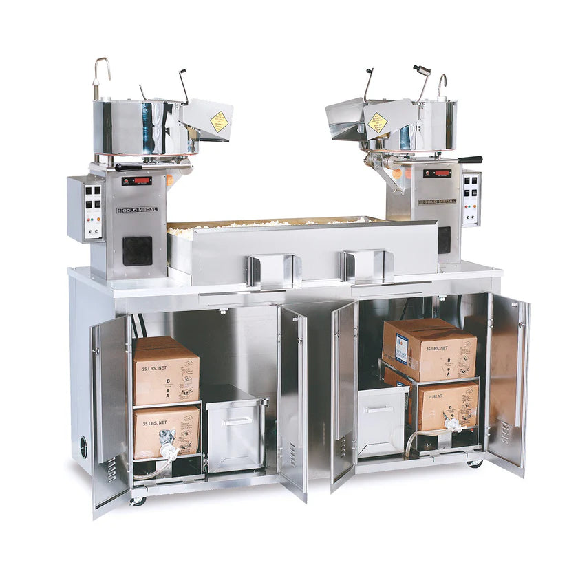 A stainless steel electric popcorn machine, the Twin Maxi Popcorn Plant, features two popping kettles with a 36 oz. capacity each. Below, four open cabinets reveal popcorn supplies and storage containers. Control panels with digital displays are on each side.