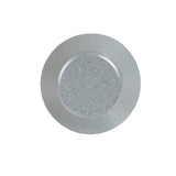 A round, clear glass plate seen from above, featuring a subtle pattern of small white and gray speckles reminiscent of a Coronado bowl. The background is completely white, highlighting the transparent and textured nature of the plate.