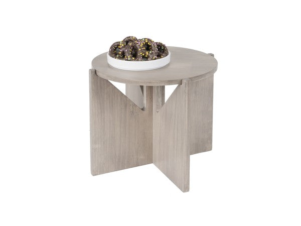A small, round, gray-washed pine wood table with intersecting panel legs. On top, there is a white plate filled with chocolate-glazed donuts topped with yellow sprinkles. The background is plain white.