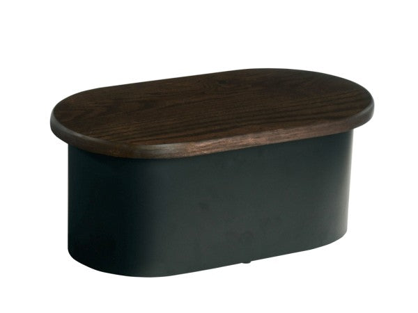An oval-shaped, modern ottoman with a dark brown oak top and a matte black metal base. The smooth wood surface contrasts with the solid black foundation, creating a sleek, minimalist design ideal for contemporary interiors.