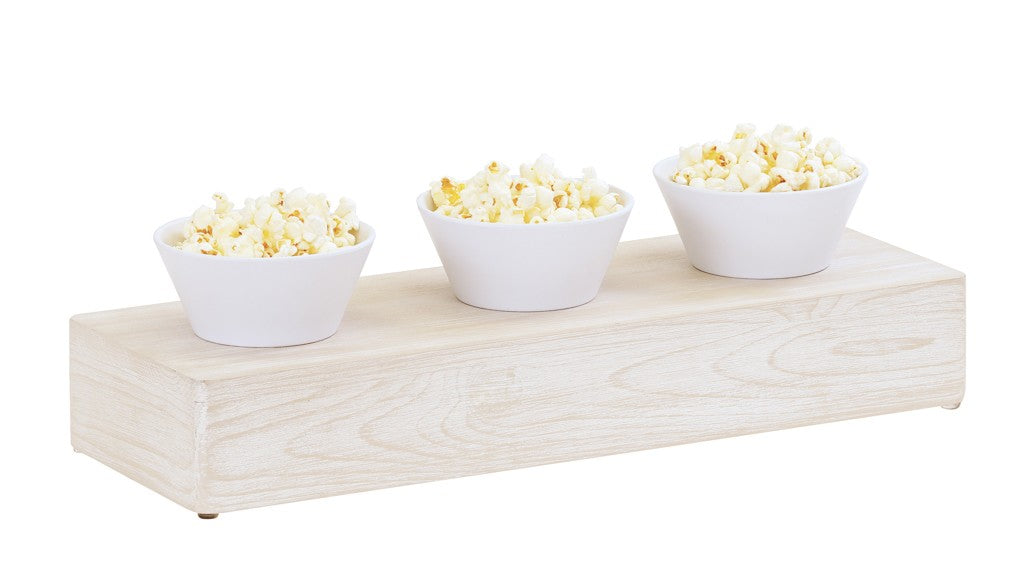 Three white bowls filled with popcorn sit in a row on a Newport white-washed pine wood riser against a white background. The bowls are evenly spaced, showcasing the platform's subtle wood grain.