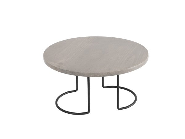 A round, light gray wooden Aspen Riser table with a smooth surface sits on two curved black wire frame metal legs that form open, semi-circular shapes at the base, creating a modern and minimalist Cal-Mil design against a plain white background.