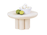 A small, round Newport pedestal riser with cylindrical legs holds a white bowl filled with white round treats. Beside the bowl are two limes, one whole and one cut in half, all set against a plain white background.