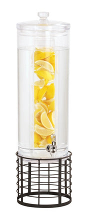 A tall, clear 3 gallon beverage dispenser filled with water and lemon wedges in a central infusion tube. It has a silver spigot near the base and sits on a round, black metal stand with an open grid design.