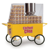 A yellow Caramel Corn Merchandiser cart with four large white wheels, a metal popcorn kettle, a clear shield, and stacks of caramel corn boxes inside. "Caramel Corn" is printed in red and white on this Gold Medal Products cart.