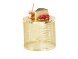 A round, shiny gold metal riser side table with a perforated pattern. On top are a wedge of cheese, a small jar of honey with a dipper, several raspberries, and a few almonds, all neatly arranged. The background is plain white.