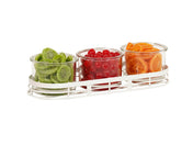 Three glass jars in a stainless steel condiment jar display, filled with green sugared gummy candies, red jelly candies, and orange dried fruit slices, arranged side by side on a white background.