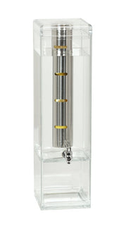A clear polycarbonate rectangular container filled with liquid, featuring a vertical metal cylinder with four yellow bands and a spout at the bottom. The transparent infusion chamber reveals the inner tube and its evenly spaced markings.