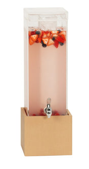 A tall, rectangular Beverage Display with a clear body and transparent lid sits in a light wood base made from water resistant upcycled rice hulls. It contains pink liquid with sliced strawberries and blueberries floating inside.