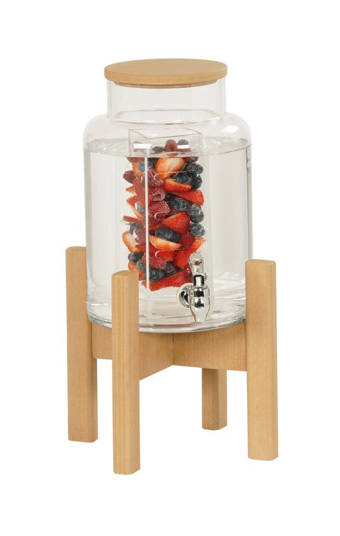 A glass beverage dispenser with a wooden lid and stand makes a stylish beverage display. An infusion chamber inside holds assorted berries like strawberries, blackberries, and blueberries. The dispenser features a silver spigot at the front.