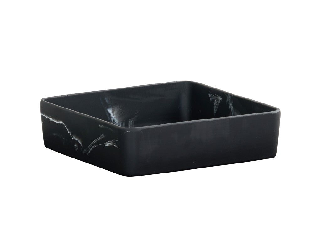 A square, deep black ceramic bowl with slightly curved sides and a subtle black swirl pattern on its exterior. The dish has a matte finish and a minimalist design, set against a plain white background.