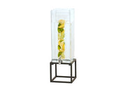 A tall, clear Infusion Beverage Dispenser with a 3 gal. polycarbonate chamber sits on a black metal stand. Filled with water and stacked slices of lemons and limes, it features a silver spigot at the bottom for easy pouring.