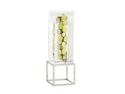 A tall, clear Infusion Beverage Dispenser with a polycarbonate chamber filled with water and lime slices stands on a geometric silver stand with a chrome plate finish. A small front spigot dispenses the drink. The background is plain white.