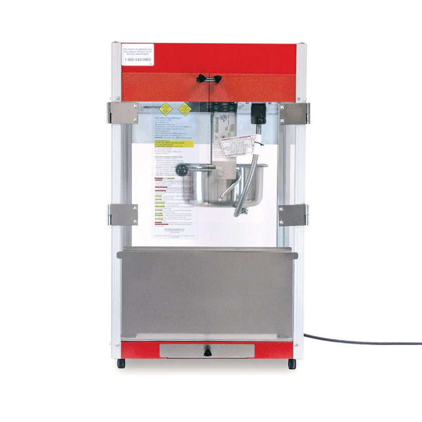 A countertop popcorn maker with a red top, transparent glass sides, an 8 oz kettle inside, and a stainless steel bottom panel. The popcorn machine is plugged in, and operating instructions are visible on a sheet inside the back panel.