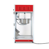 A red and silver countertop popcorn machine with a glass enclosure, 8 oz kettle inside, hinged glass door on the left, and a black power cord extending from the bottom right. The interior is empty and clean.